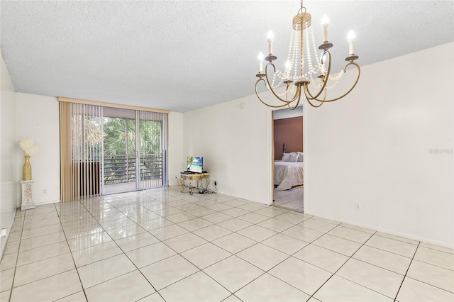 spare room with a chandelier, a textured ceiling, and light tile patterned floors