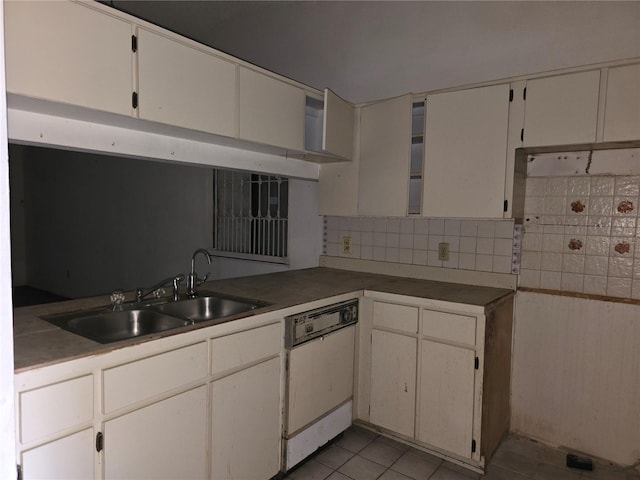 kitchen featuring tasteful backsplash, white cabinetry, white dishwasher, light tile patterned flooring, and sink