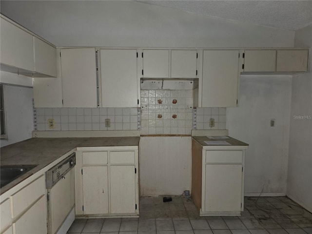 kitchen with lofted ceiling, dishwasher, white cabinetry, and backsplash