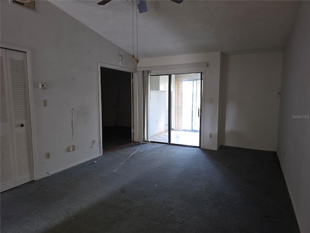 spare room with dark colored carpet, lofted ceiling, a textured ceiling, and ceiling fan