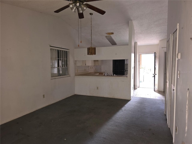 unfurnished living room with ceiling fan, a textured ceiling, lofted ceiling, and dark carpet