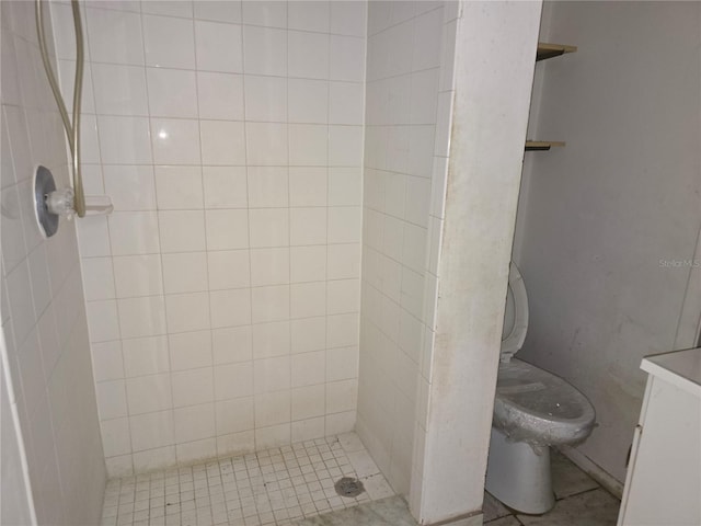 bathroom featuring vanity, a tile shower, and toilet