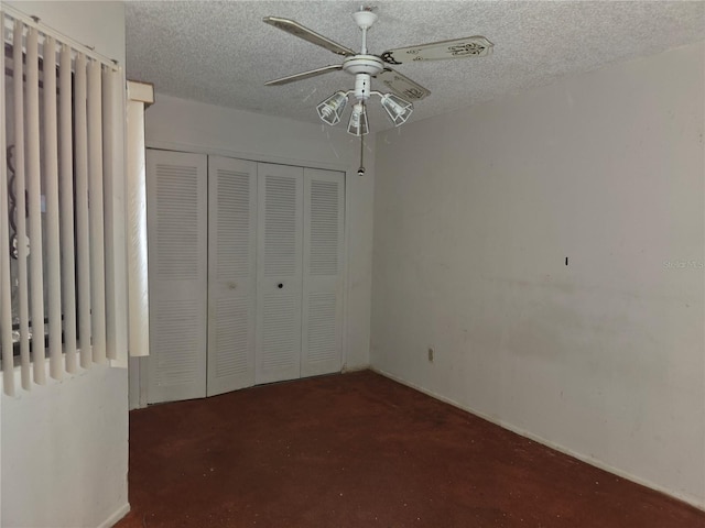 unfurnished bedroom with dark carpet, a textured ceiling, a closet, and ceiling fan