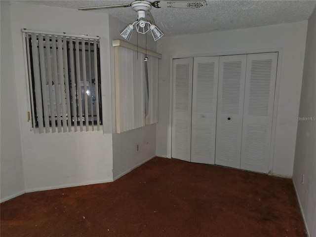 unfurnished bedroom featuring dark carpet, a textured ceiling, a closet, and ceiling fan