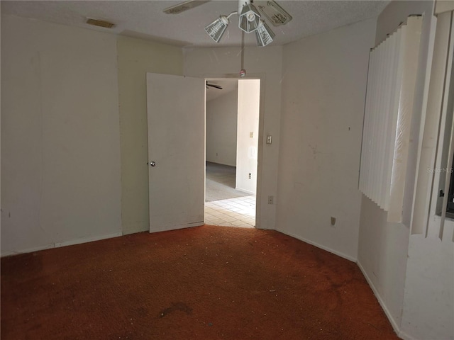 empty room featuring ceiling fan, carpet, and a textured ceiling