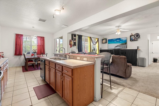 kitchen featuring hanging light fixtures, sink, a breakfast bar, light colored carpet, and a kitchen island with sink