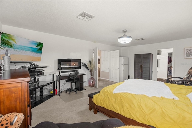 bedroom with a textured ceiling, light carpet, and white fridge