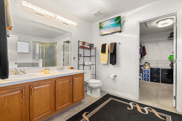 bathroom with tile patterned floors, vanity, a textured ceiling, an enclosed shower, and toilet