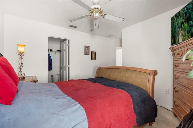 carpeted bedroom featuring ceiling fan and a textured ceiling