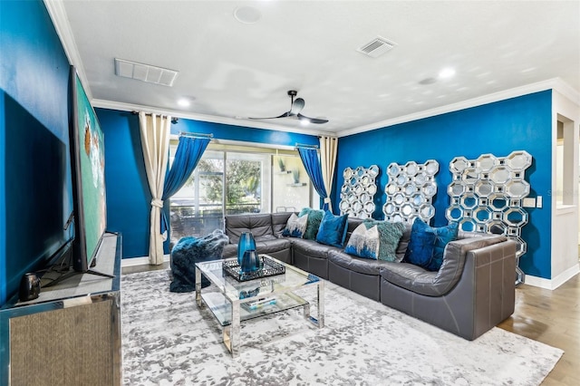 cinema room with ornamental molding, wood-type flooring, and ceiling fan