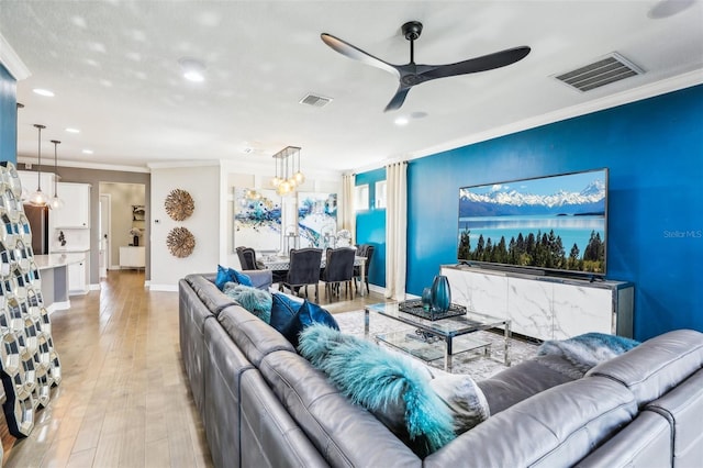 living room with crown molding, light wood-type flooring, and ceiling fan