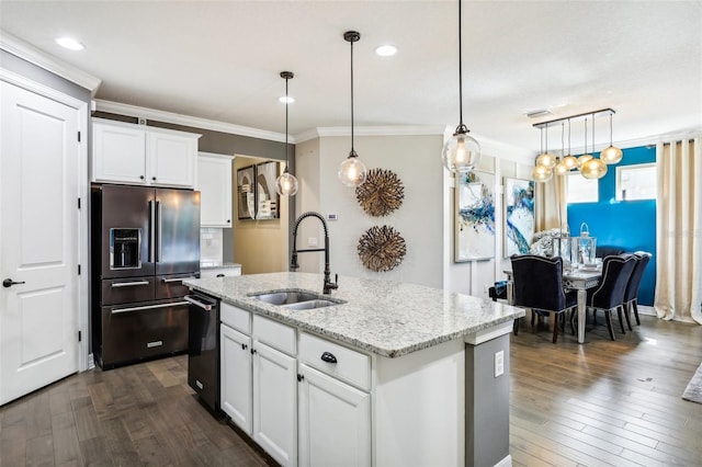 kitchen with white cabinets, pendant lighting, high end fridge, and an island with sink