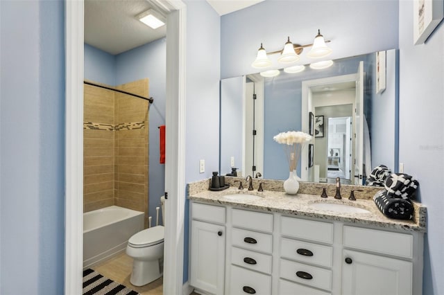 full bathroom featuring toilet, tiled shower / bath combo, vanity, and a textured ceiling