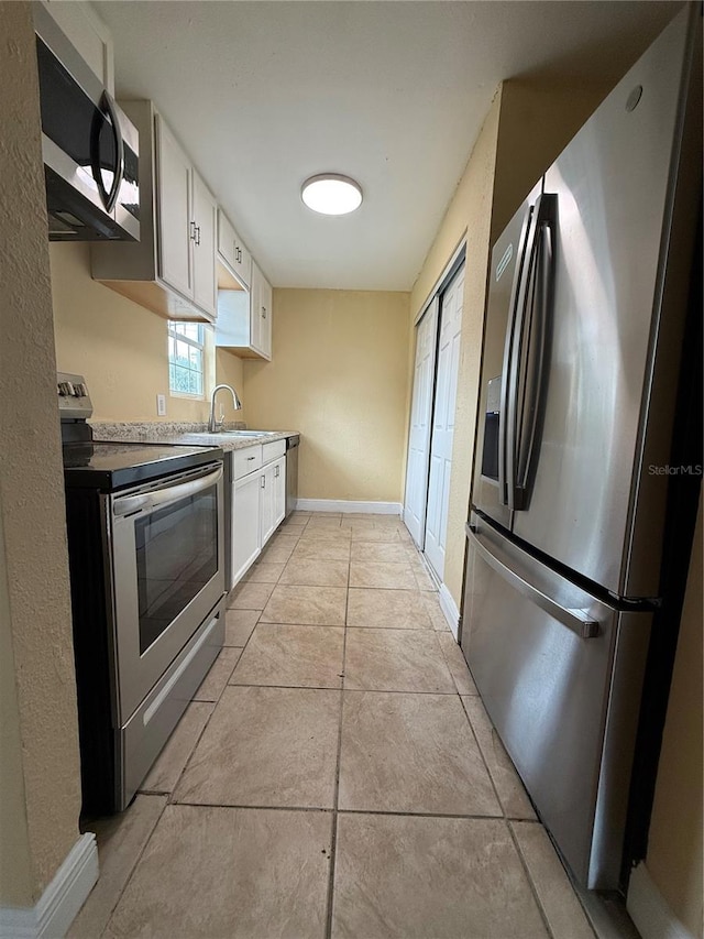 kitchen with sink, appliances with stainless steel finishes, white cabinets, and light tile patterned floors