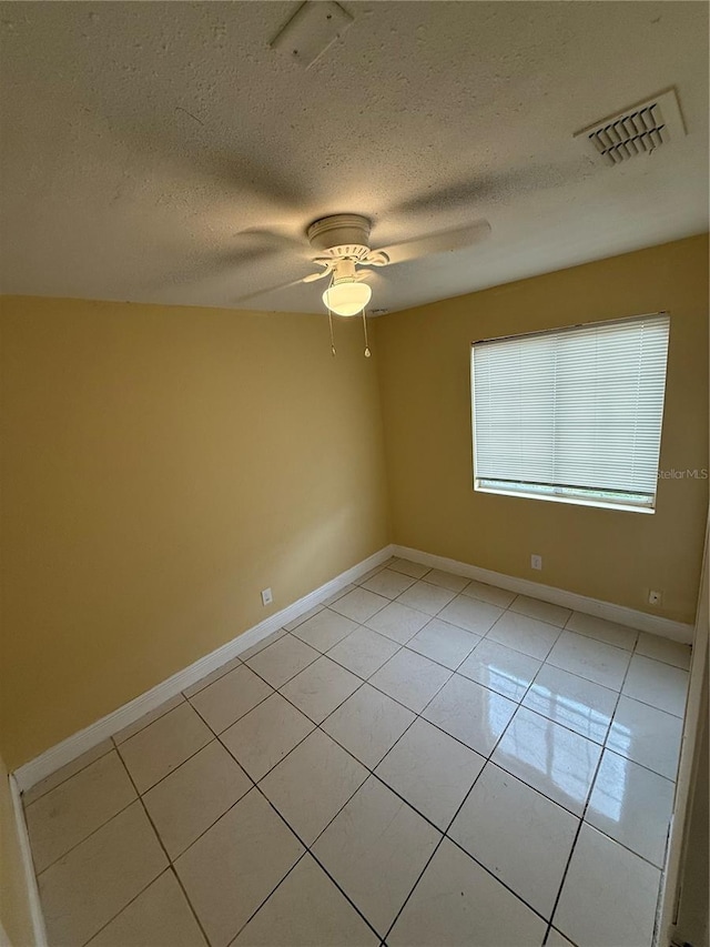 tiled empty room with ceiling fan and a textured ceiling