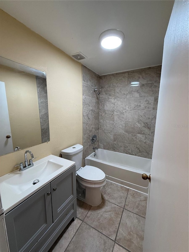 full bathroom featuring toilet, tiled shower / bath, vanity, and tile patterned flooring