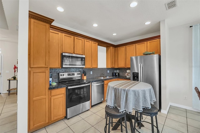 kitchen with light tile patterned flooring, stainless steel appliances, and backsplash