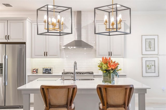 kitchen featuring stainless steel fridge, a kitchen breakfast bar, hanging light fixtures, and wall chimney exhaust hood