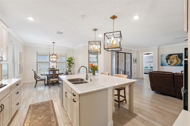 kitchen featuring hanging light fixtures, a wealth of natural light, light wood-type flooring, and a kitchen island with sink