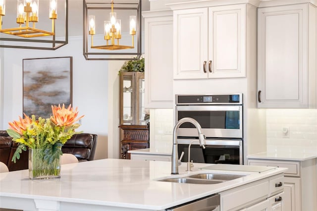 kitchen featuring stainless steel appliances, decorative light fixtures, an inviting chandelier, and white cabinetry