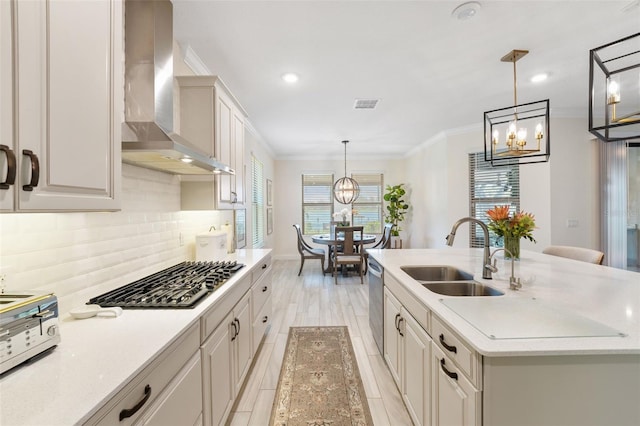 kitchen featuring pendant lighting, wall chimney range hood, sink, and a wealth of natural light