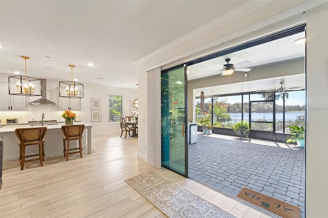 doorway to outside featuring ceiling fan, crown molding, a water view, and light hardwood / wood-style floors