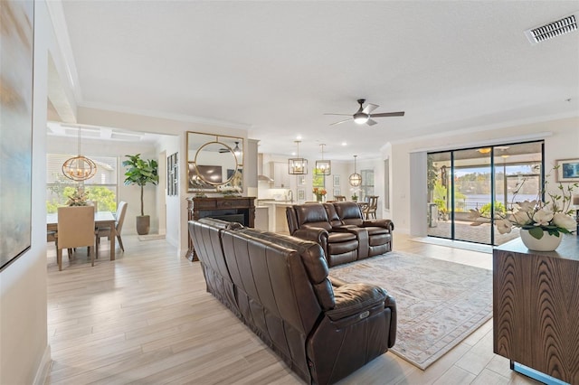 living room with crown molding, light hardwood / wood-style floors, and ceiling fan with notable chandelier