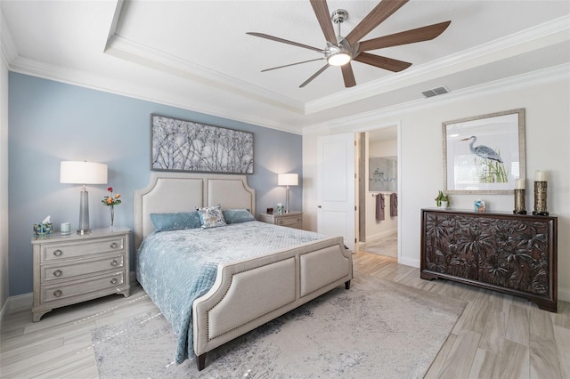 bedroom with ensuite bath, a raised ceiling, ceiling fan, crown molding, and light hardwood / wood-style flooring