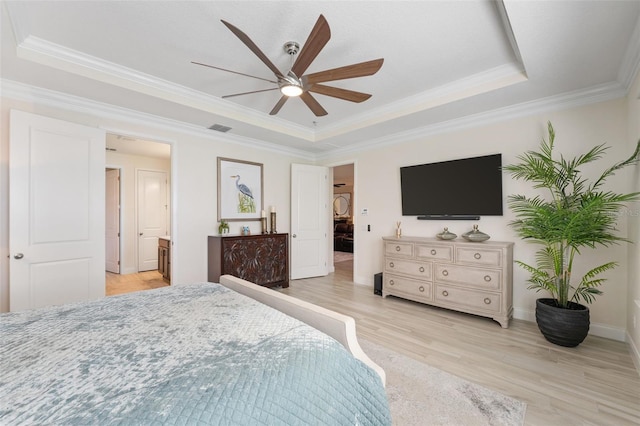 bedroom with ceiling fan, a raised ceiling, ensuite bathroom, light hardwood / wood-style floors, and ornamental molding