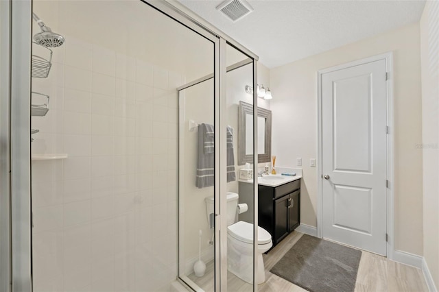 bathroom with wood-type flooring, vanity, toilet, and an enclosed shower