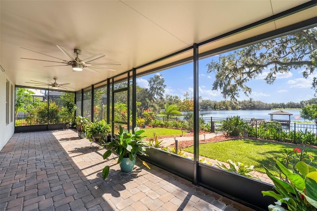 unfurnished sunroom featuring a wealth of natural light, ceiling fan, and a water view