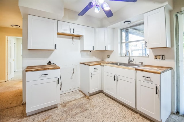 kitchen featuring white cabinets, butcher block countertops, ceiling fan, and sink