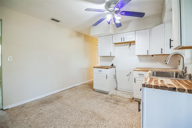 kitchen featuring butcher block counters, white cabinetry, sink, and ceiling fan