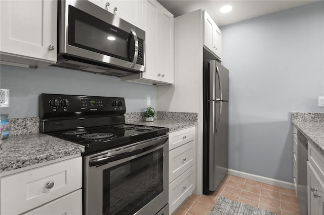 kitchen with stainless steel appliances, white cabinetry, light stone countertops, and light tile patterned floors