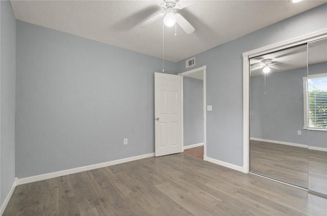 unfurnished bedroom with ceiling fan, wood-type flooring, and a closet