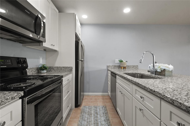 kitchen with stainless steel appliances, sink, white cabinets, and light stone counters