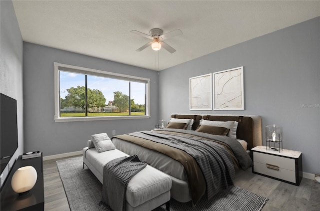 bedroom with ceiling fan, a textured ceiling, wood finished floors, and baseboards