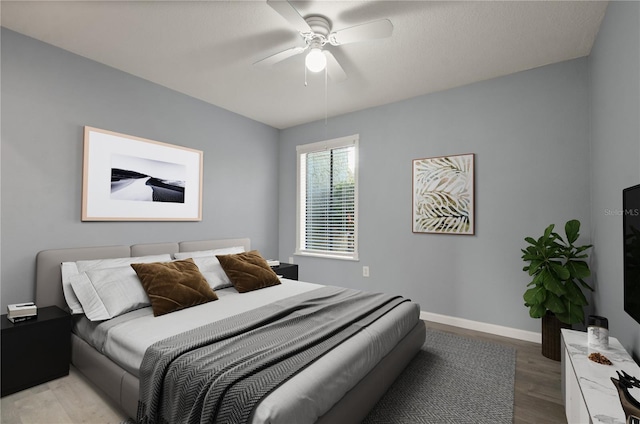 bedroom with light wood-type flooring, ceiling fan, and baseboards