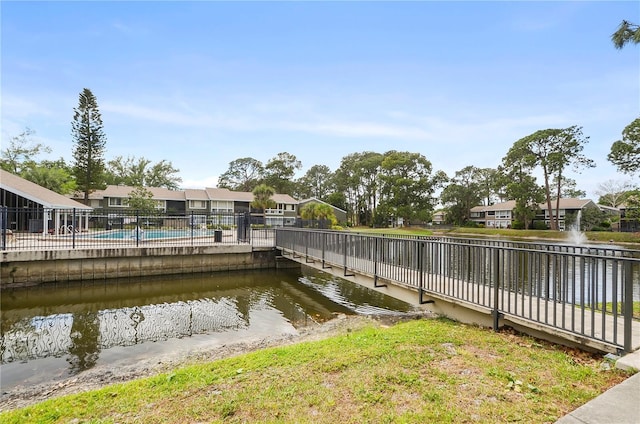 view of dock featuring a water view, fence, a residential view, and a community pool