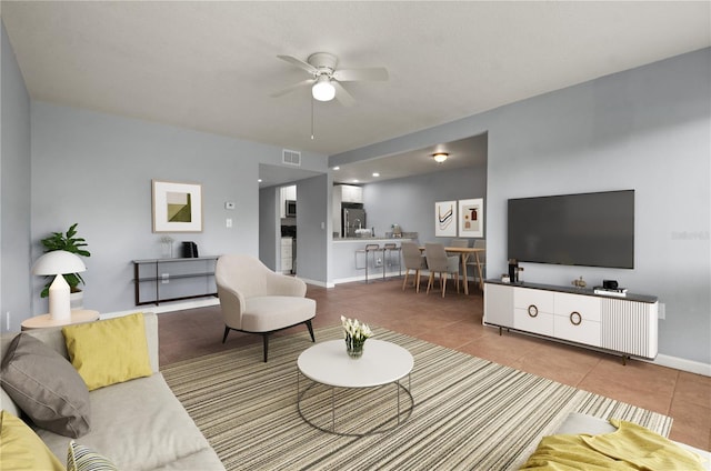 living room with baseboards, a ceiling fan, visible vents, and tile patterned floors