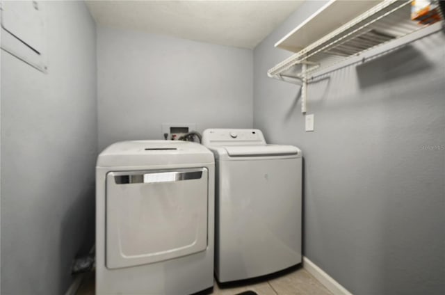 laundry area with light tile patterned floors, laundry area, independent washer and dryer, and baseboards