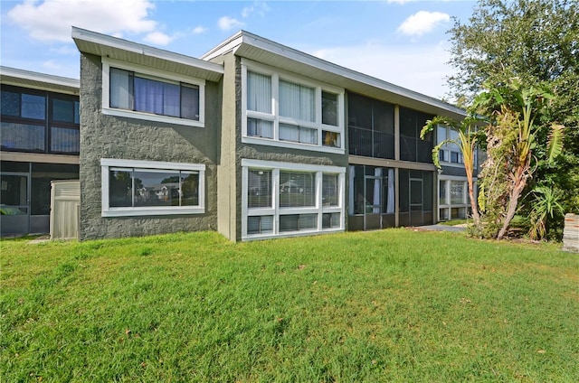 back of house featuring a lawn and stucco siding