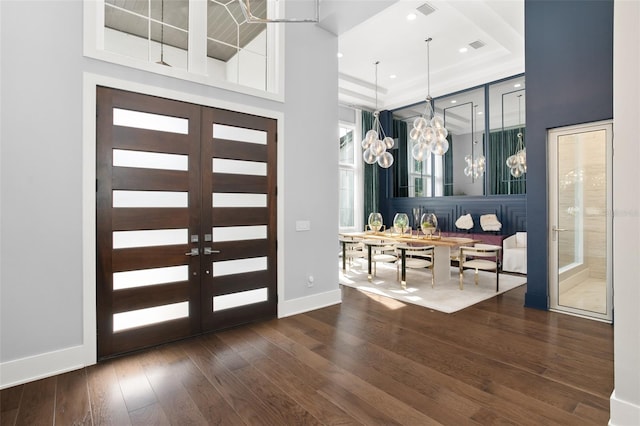 foyer entrance with a towering ceiling, dark wood-type flooring, a tray ceiling, and a chandelier