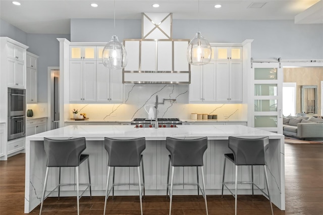 kitchen with light stone countertops, a large island, white cabinetry, and dark hardwood / wood-style flooring