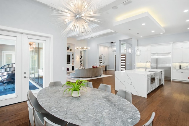 dining space with dark wood-type flooring, a notable chandelier, french doors, and sink