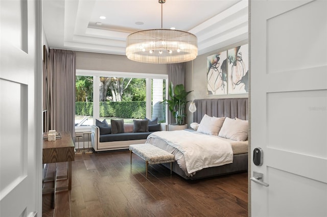 bedroom with dark wood-type flooring, a tray ceiling, and an inviting chandelier