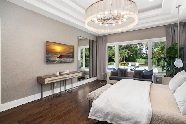 bedroom with a chandelier, dark wood-type flooring, and a raised ceiling