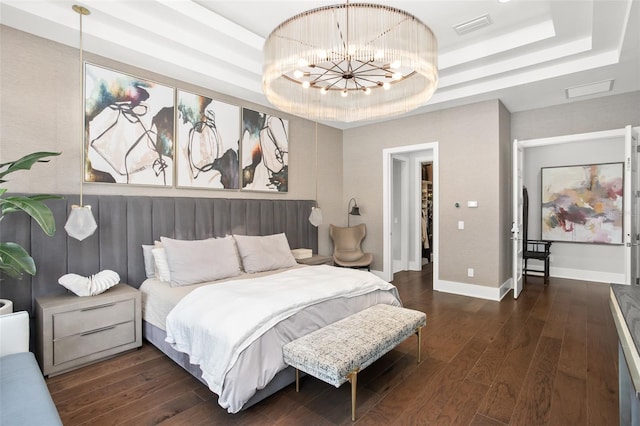 bedroom with a notable chandelier, a tray ceiling, and dark hardwood / wood-style flooring