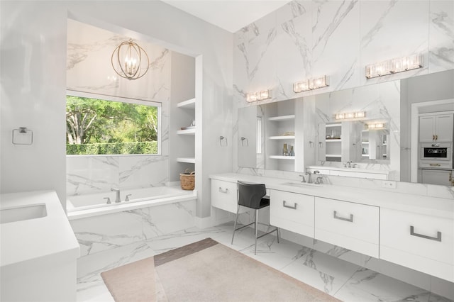 bathroom with vanity, built in shelves, a notable chandelier, and tiled tub