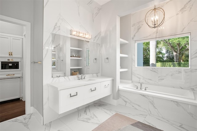 bathroom featuring vanity, a chandelier, tiled bath, and built in shelves